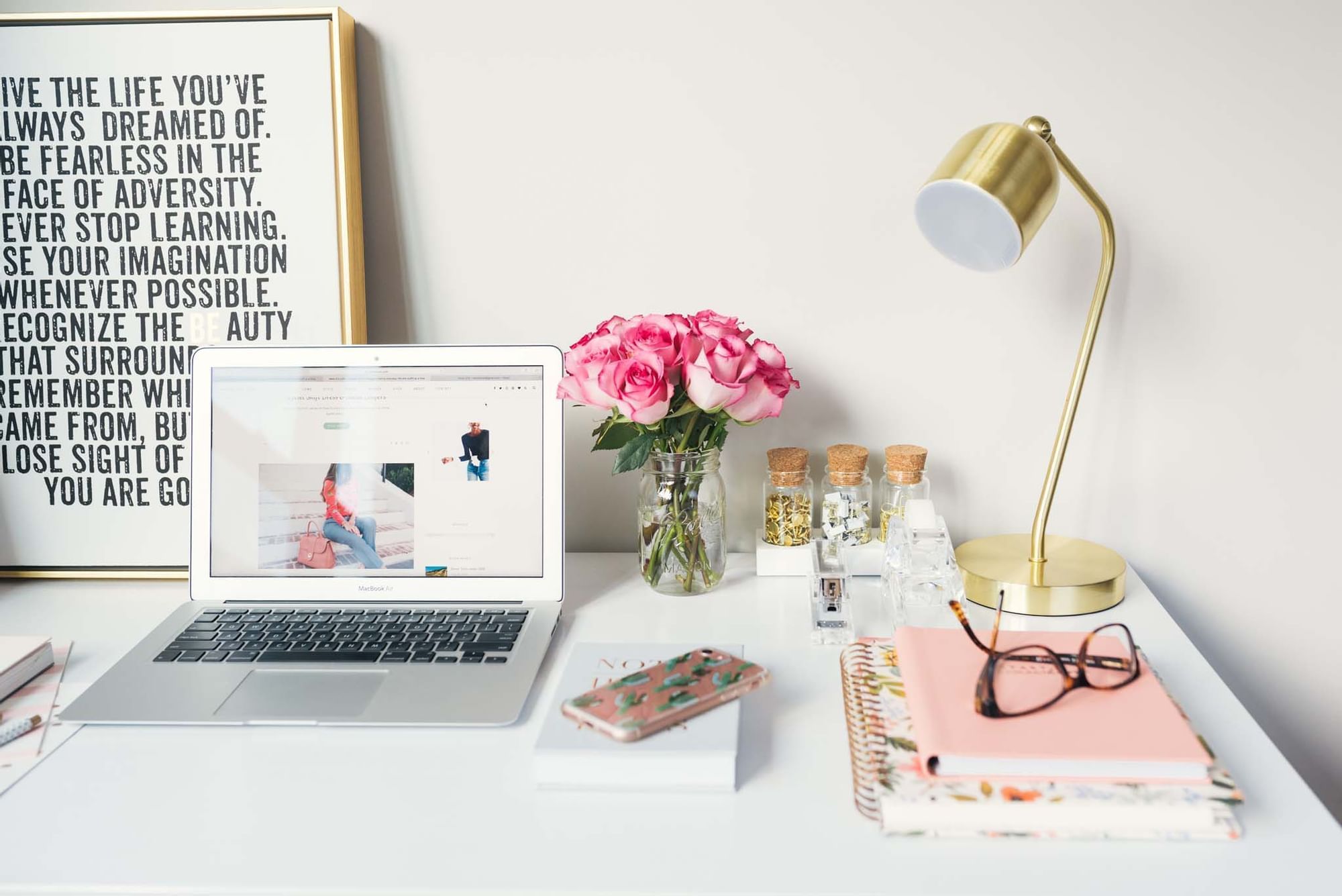 A stylish desk with a laptop, bouquet of roses and gold lamp at Sunway Hotel Hanoi